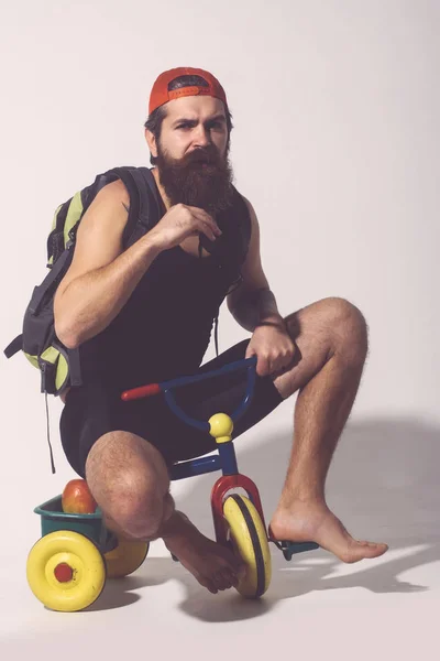 Barbudo sério homem com saco, maçã na bicicleta brinquedo — Fotografia de Stock