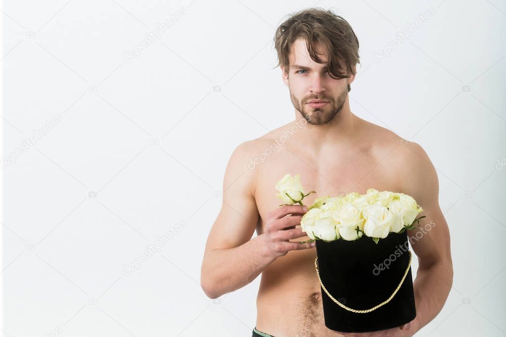 Bearded sexy macho holding roses in black gift box