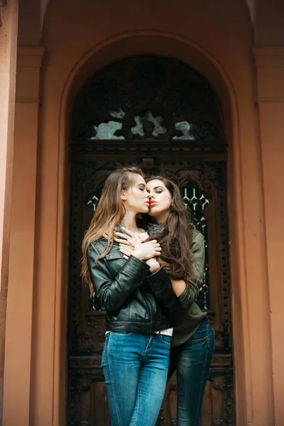 Chicas guapas besándose y abrazándose en jeans en la puerta principal — Foto de Stock