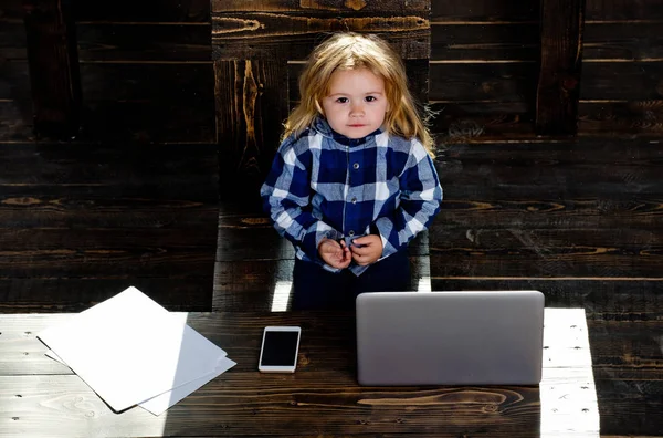 Niño lindo en la oficina con el ordenador portátil, teléfono, hoja de papel — Foto de Stock