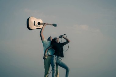 Güzel kadının yakışıklı adamla mikrofon ile gitar şarkı