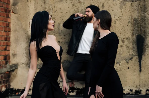 Mooie meisjes kijken brutale man met baard drinken van wijn — Stockfoto