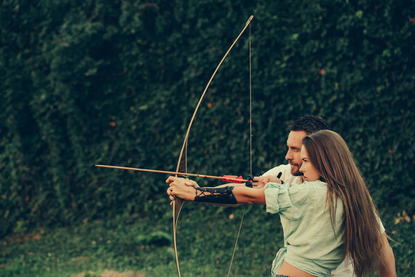 мужчина и симпатичная женщина стреляют из лука и стрелы
