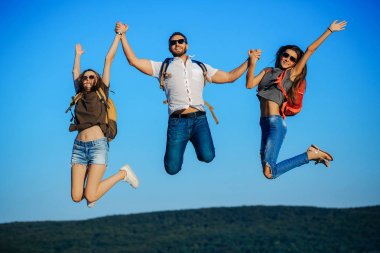 Arkadaş, mutlu turist dağın tepesinde mavi gökyüzü atlama