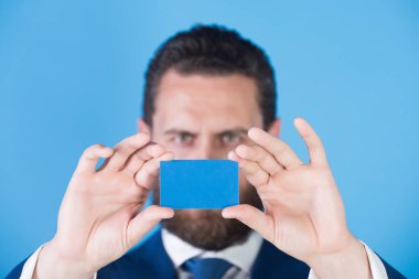 mavi arka plan üzerinde kredi kartı tutan adam