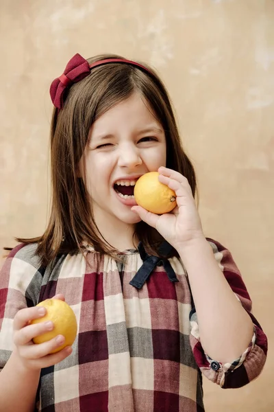 子供やレモンを食べて目をまばたきを持つ少女 — ストック写真