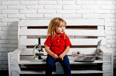 dizüstü bilgisayar ve mikroskop ve kulaklık bankta bir öğrenci çocuk