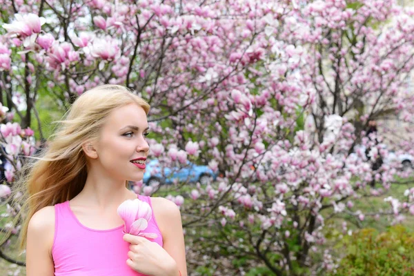Jonge mooie vrouw in de buurt van magnoliaboom met bloemen — Stockfoto
