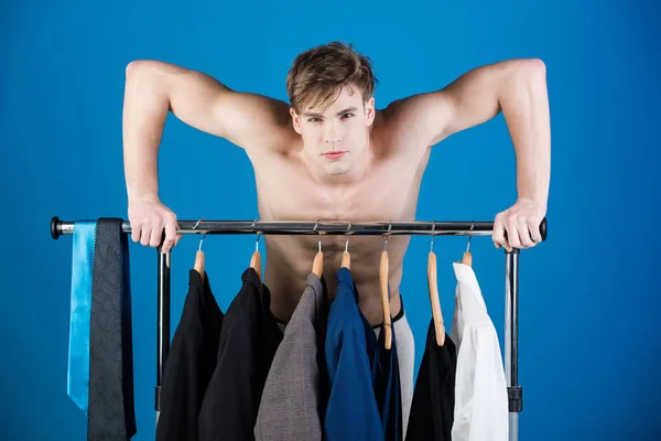 Ξυρισμένο άνθρωπος με γυμνό κορμό μυϊκή στέκεται στην ντουλάπα κρεμάστρα — Φωτογραφία Αρχείου