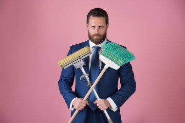 süpürge üzerinde pembe bir arka plan temizleme ile genç yakışıklı işadamı