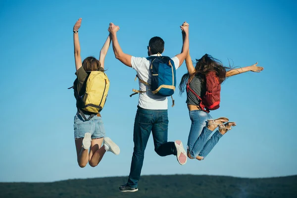 Drie vrienden springen op de bergtop op blauwe hemel — Stockfoto