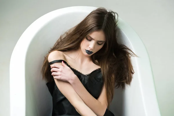 Woman in dress with long hair, black lipstick in bath — Stock Photo, Image