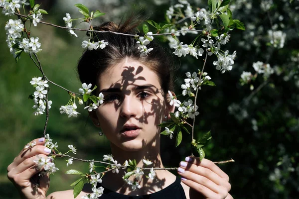 Mädchen mit Rahmen aus blühenden Blumen im Frühlingsgarten — Stockfoto