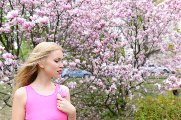 Mulher mantenha a flor de magnólia na árvore florescente, jardim de primavera — Fotografia de Stock