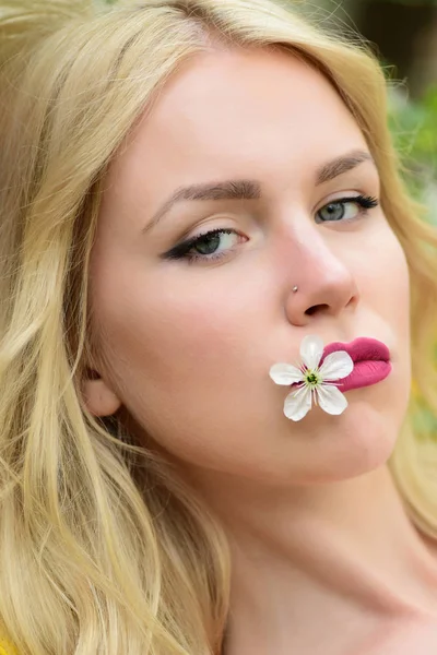 Jovem menina segura na boca uma flor de cereja branca — Fotografia de Stock