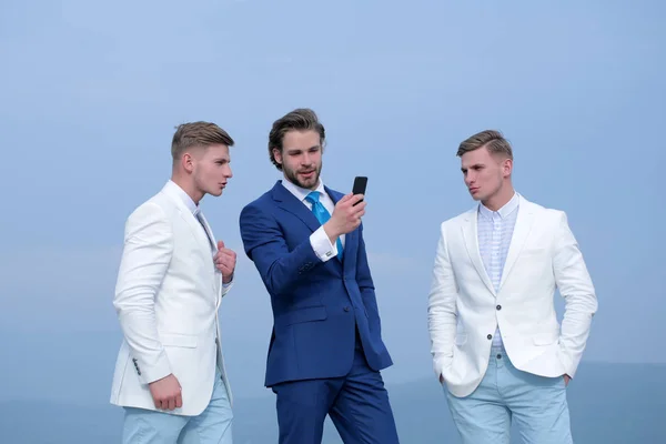 Zakenman met mobiele of mobiele telefoon spreken met twee mannen — Stockfoto