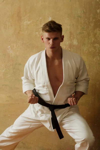 Karate mannen i en kimono som poserar på beige bakgrund — Stockfoto