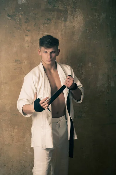 Fiatal karate mester fehér kimonó csomagolás fekete öv — Stock Fotó
