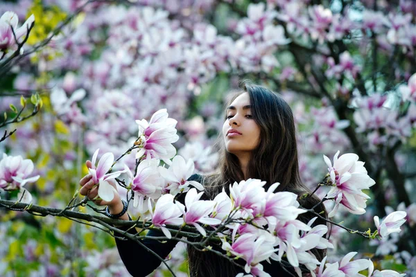 Woman with long, brunette hair posing at magnolia tree — Stock Photo, Image