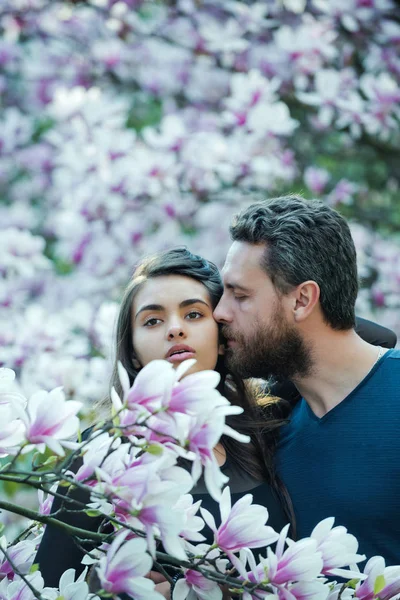 Влюбленная пара, мужчина целует женщину на цветущих деревьях, магнолия — стоковое фото