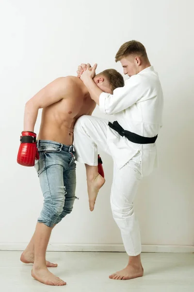Мужчины, сражающиеся в кимоно карате и боксерских перчатках — стоковое фото