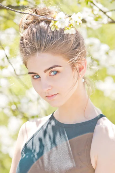 Mulher bonita com olhos azuis posando entre flores brancas, florescentes — Fotografia de Stock