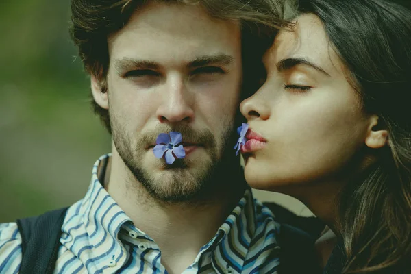 Flickvän och pojkvän med blå blommor i munnar — Stockfoto