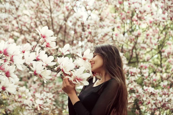 Flicka med långa, brunett hår njuter magnolia blomma blomma — Stockfoto