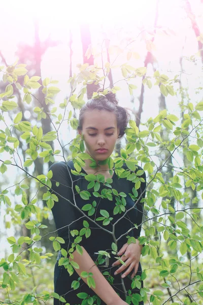Adorable chica escondido en verde árbol hojas en primavera bosque —  Fotos de Stock