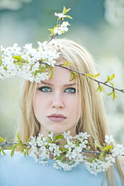 Kobieta o niebieskich oczach pozowanie z białym, kwitnących kwiatów — Zdjęcie stockowe