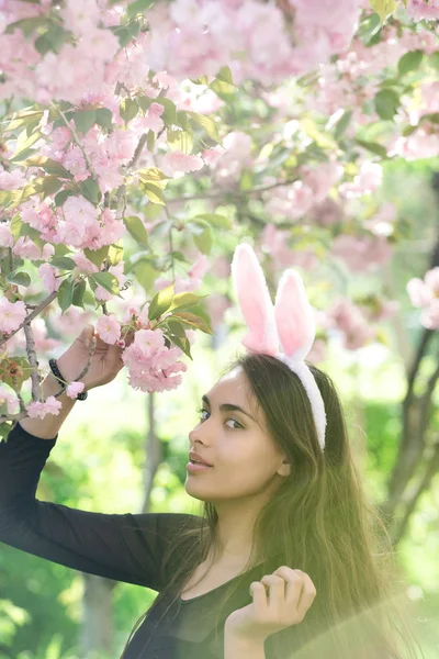 Bunny ears on woman with spring sakura flowers — Stock Photo, Image