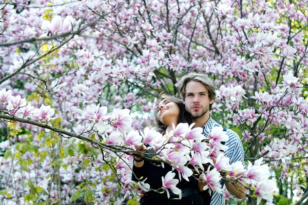 Handsome man and pretty girl enjoying magnolia flower blossom