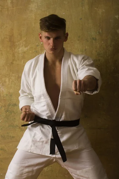 Man utbildning karate i vit kimono på beige bakgrund, sport — Stockfoto