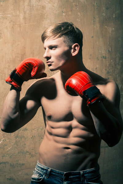 man boxer with red boxing gloves in muscular arms