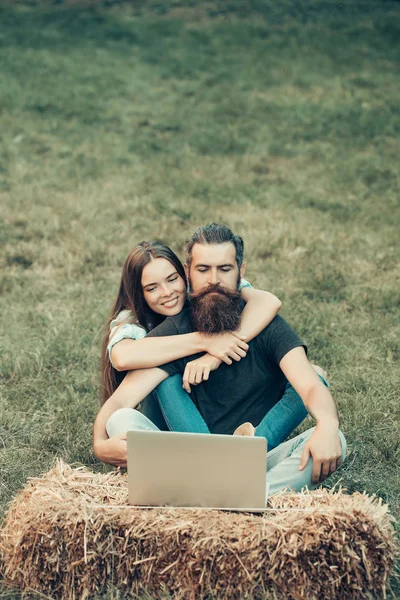 Pareja en el amor, chica y hombre barbudo utilizando el ordenador portátil al aire libre — Foto de Stock