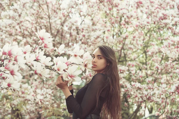 Woman with long, brunette hair posing at magnolia tree — Stock Photo, Image