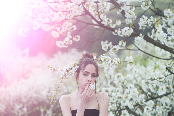 Beautiful young woman enjoying smell in a flowering spring garden