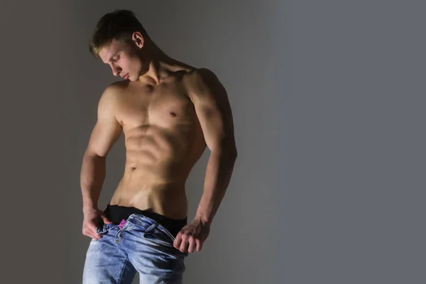 Hombre sexy con desnudo, fuerte torso despojando pantalones vaqueros azules — Foto de Stock