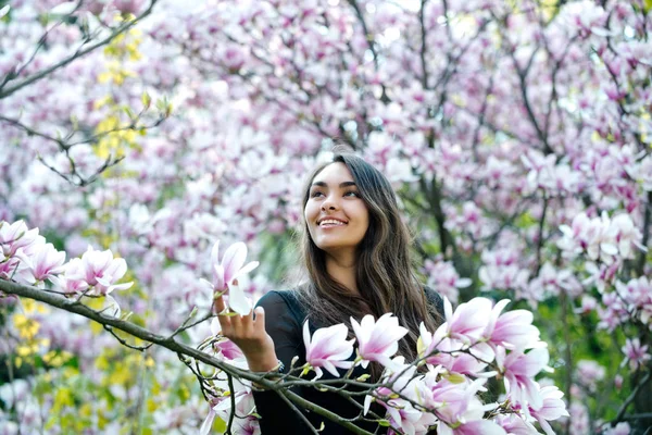 Menina feliz sorrindo para a árvore de magnólia com flores florescentes — Fotografia de Stock