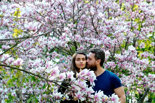 Frau umarmt glücklich lächelnden Mann an Magnolienbäumen — Stockfoto