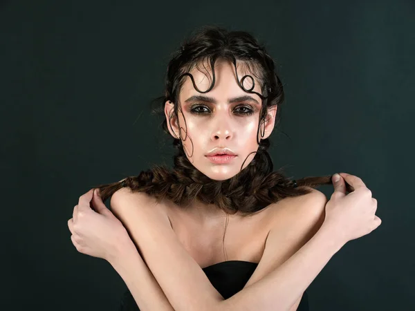 Жінка з блискучим макіяжем, що тримає коси з схрещеними руками — стокове фото