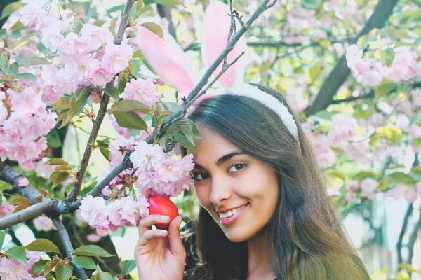 Meisje met bunny oren glimlachend met rode ei, sakura — Stockfoto