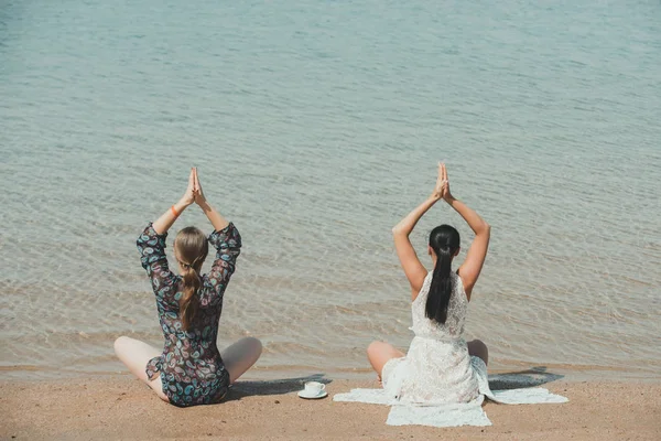 Mujeres meditando en yoga posan con taza de café en el agua —  Fotos de Stock