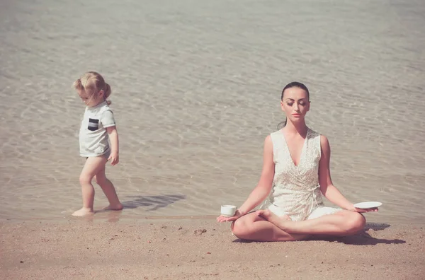 child and woman meditating in yoga pose with coffee cup