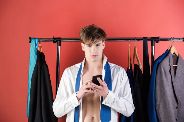 Geschoren man met gespierde torso op kledingkast hanger met telefoon — Stockfoto