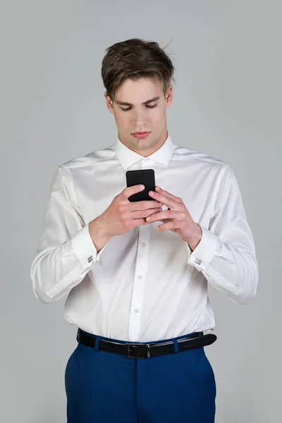 Liikemies valkoisessa paidassa, siniset housut kalvosinnapilla käytä puhelinta — kuvapankkivalokuva