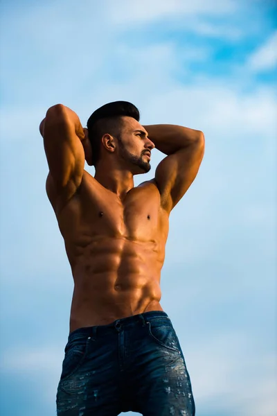 Mannen med muskulös kropp på blå himmel — Stockfoto