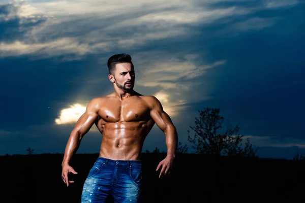 Entrenador hombre con el cuerpo muscular en el cielo azul — Foto de Stock