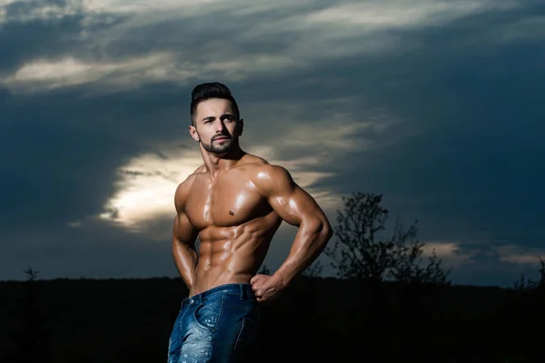 Entrenador hombre con el cuerpo muscular en el cielo azul — Foto de Stock