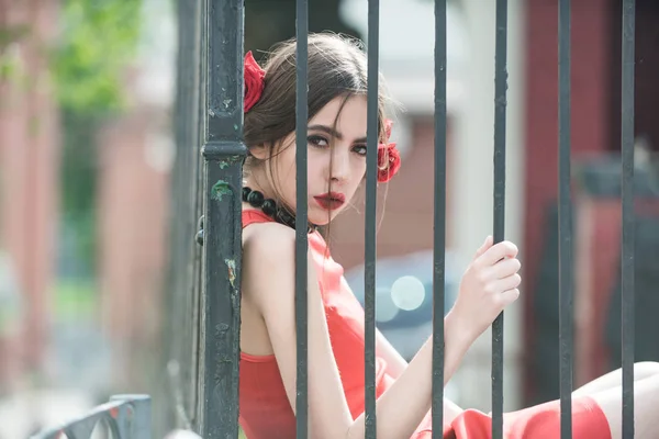Дівчина з трояндою у волоссі на залізному паркані — стокове фото